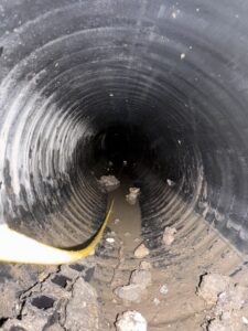 Dallas Drainage Pros inspecting a large drain pipe on a new construction build project